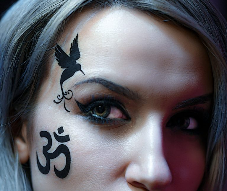Fake tattoo face. Bird tattoo by the eye.